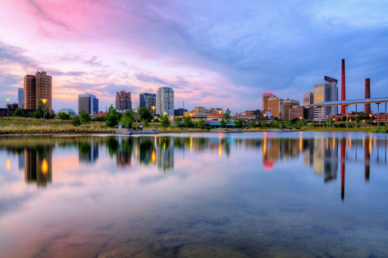 Birmingham Alabama skyline at dusk, city lights reflected off of water, purple and blue sky