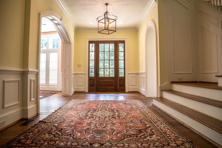 Entryway to a nice home, large rug on wooden floors next to the stairs