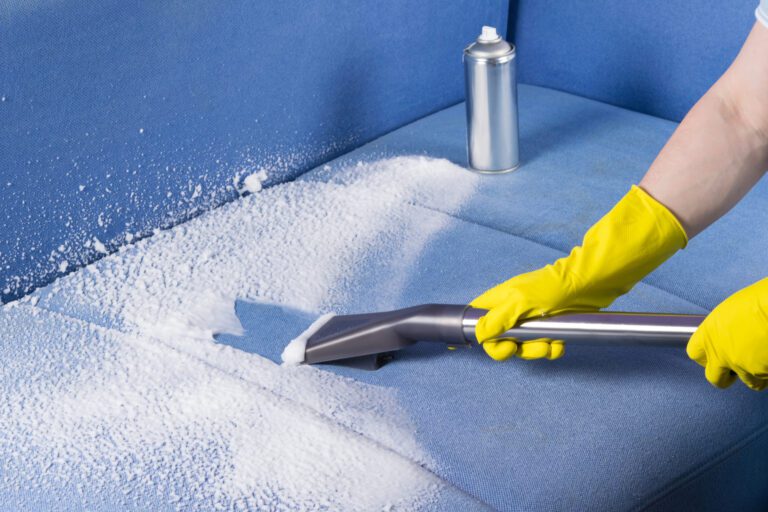 Blue couch being cleaned with upholstery foam and an extended brush